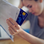 Stressed young sitting Asian woman hands holding credit card