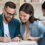 Happy family couple signing contract with agent