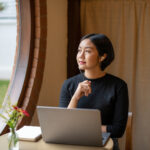 Freelance businesswoman sitting in front of her considering work at cafe, thinking new project work plan.