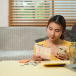 Young woman paying domestic bills or managing online banking on her mobile phone