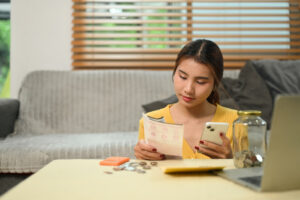Young woman paying domestic bills or managing online banking on her mobile phone